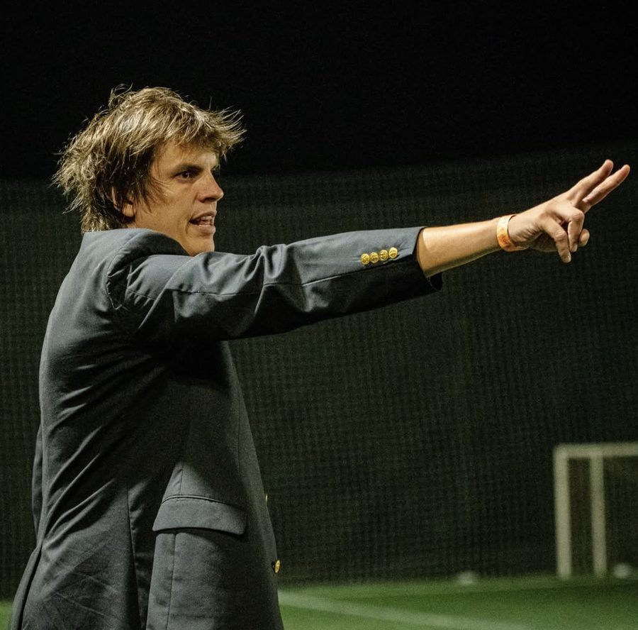 Gustav Salvestrini señalando en la cancha, de noche, con saco